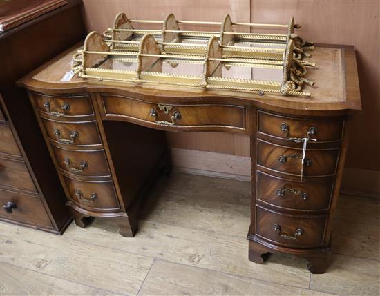 A George III style mahogany serpentine fronted kneehole desk, fitted nine small drawers W.115cm